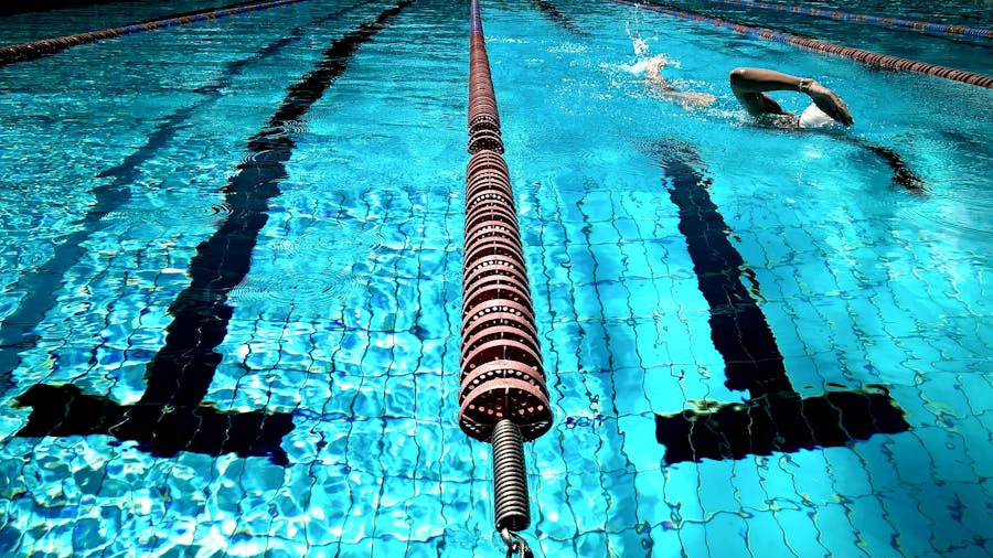 Swim lanes in an outdoor pool with a swimmer in the distance